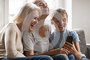 Laughing three generations of women having fun using smartphone