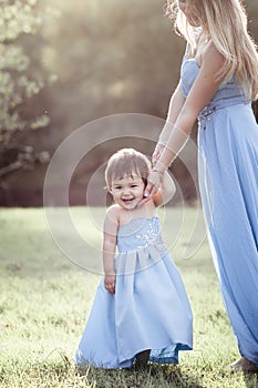 Laughing toddler girl in blue long dress with mom