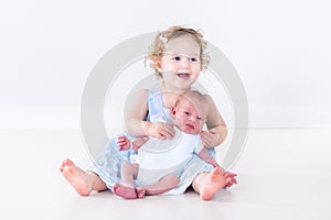 Laughing toddler girl with her newborn baby brother