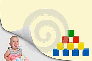 Laughing toddler girl and pyramid of wooden toy cubes