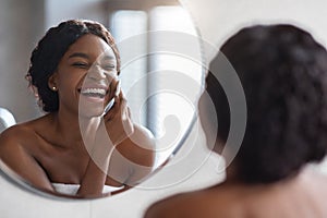Laughing topless black woman removing makeup at bathroom
