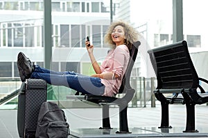 Laughing traveler sitting with feet on suitcase