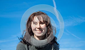 A laughing woman against a blue sky.