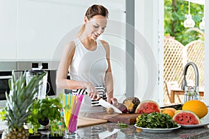 Laughing woman cutting kiwi