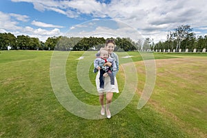 Laughing woman holding cheerful baby boy and having fun on grass