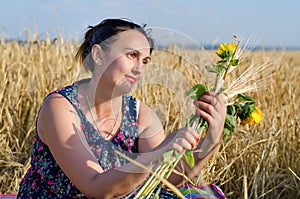 Laughing woman holding flowers in a wheat field