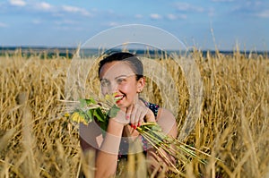 Laughing woman holding flowers in a wheat field