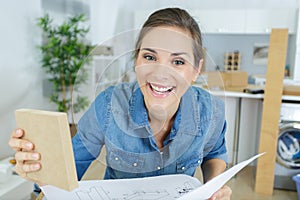 Laughing woman holding instructions for assembling furniture