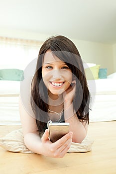 Laughing woman listening music lying on the floor