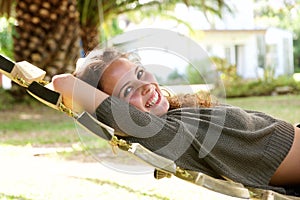 Laughing woman lying in hammock in front of palm tree