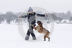 Laughing woman plays with boxer dog in winter park. Love and friendship