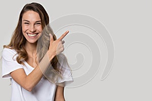 Laughing woman pose over white grey background pointing at copyspace