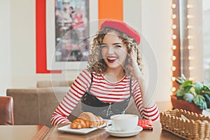 Laughing woman in red beret sitting in cafe