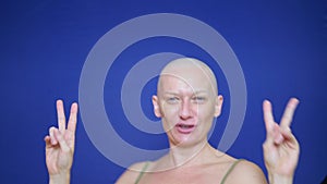 Laughing woman with a shaved head looking at camera on a blue background. the woman rejoices that she was able to