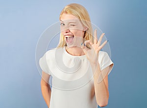 Laughing woman showing OK gesture. Woman isolated on white background showing ok sign with fingers. Funny young girl