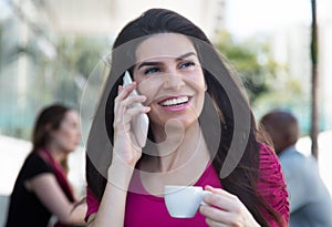 Laughing woman speaking at phone outdoor in a restaurant