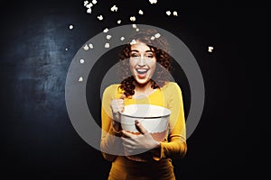 Laughing woman throwing up popcorn up in the air