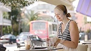 Laughing woman wearing a headset in outdoor cafe