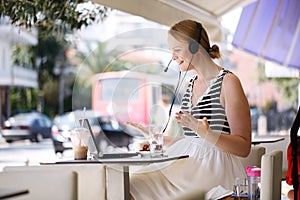 Laughing woman wearing a headset in outdoor cafe