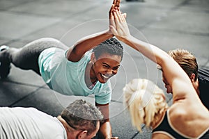 Laughing women high fiving while planking in a gym class