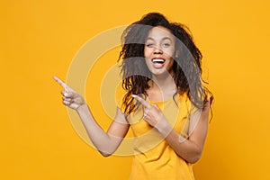 Laughing young african american woman in casual t-shirt posing isolated on yellow orange wall background studio portrait