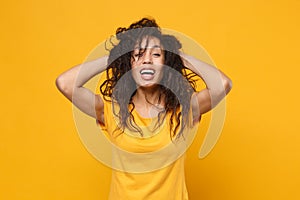 Laughing young african american woman girl in casual t-shirt posing isolated on yellow orange background in studio