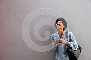 Laughing young african american woman with mobile phone