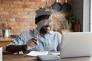 Laughing young african guy enjoy good joke on laptop screen