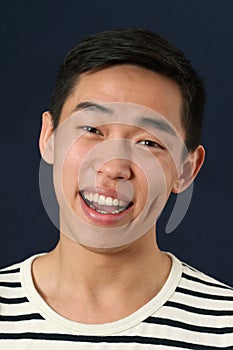 Laughing young Asian man looking at camera