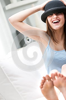 Laughing young barefoot woman in a bowler hat