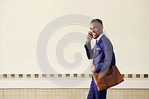 Laughing young business man walking and talking on cell phone