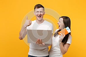 Laughing young couple friends in white t-shirts posing isolated on yellow orange background. People lifestyle concept