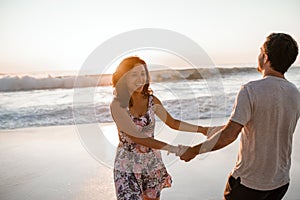 Laughing young couple having fun at the beach at sunset