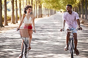 Laughing young couple riding bicycles on a sunny road