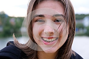 Laughing young girl with brown hair fluttering on a wind