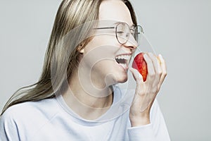 Laughing young girl eating an apple. Close-up. Healthy nutrition and vitamins