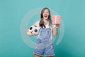 Laughing young girl football fan watching match support favorite team with soccer ball bucket of popcorn isolated on