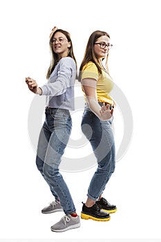 Laughing young girl friends are dancing. Freedom of movement. Isolated on white background. Vertical