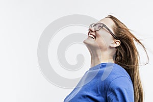 Laughing young girl with glasses in a blue t-shirt. Happiness and joy. White background. Space for text