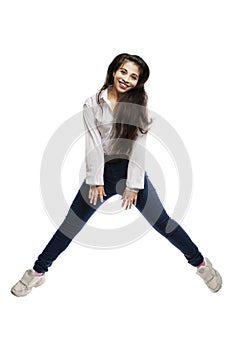 Laughing young girl with long hair is jumping. Brunette in a white shirt and jeans. Activity and energy. Isolated on a white