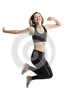 Laughing young girl in sportswear is jumping emotionally. Isolated on a white background. Full height. Vertical. Expression and