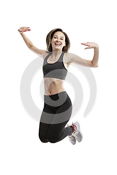 Laughing young girl in sportswear is jumping. Sport and movement. Isolated on a white background. Vertical