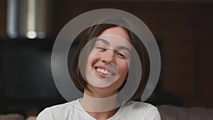Laughing young girl watching TV comedy show, looking at camera, giggling. Headshot portrait. Positive emotions