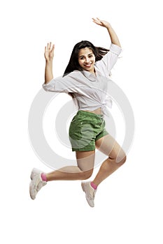 Laughing young girl in a white shirt and green shorts is jumping. Brunette with long hair. Isolated on a white background.