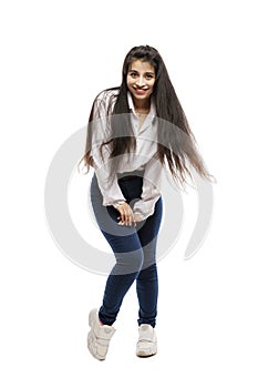 Laughing young girl in a white shirt and jeans. Brunette with long hair. Isolated on a white background. Vertical. Full height