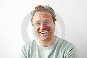 Laughing young guy standing against white wall