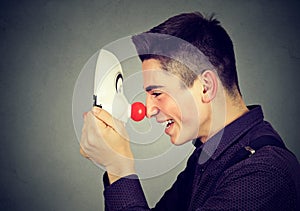 Laughing young man with clown mask