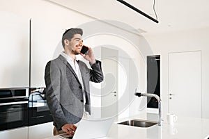 Laughing young man in suit talking on mobile phone