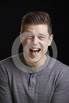 Laughing young white man looks to camera, vertical portrait