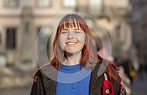Laughing young woman 20-25 years old with dyed red hair and a little overweight on the background of the city, close-up street por